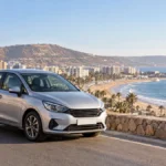 Voiture de location sur une route côtière de la région d’Agadir avec l’océan en arrière-plan.