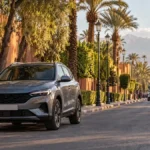 Voiture compacte dans une avenue de Marrakech, avec palmiers et architecture ocre